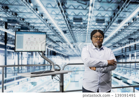 Woman in microchip smart factory using MES software to optimize production lines workflow. African american supervisor tracking semiconductor production hardware performance metrics Woman in microchip smart factory using MES software to optimize production lines workflow. African american supervisor tracking semiconductor production hardware performance metrics 139391491