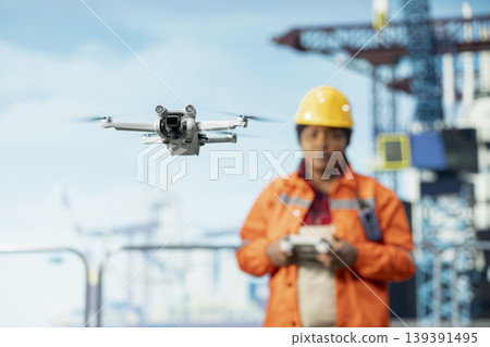 Drilling rig specialist using drone for quick overview and evaluation of hard to reach areas. Offshore platform worker uses remote control UAV for preventive maintenance planning Drilling rig specialist using drone for quick overview and evaluation of hard to reach areas. Offshore platform worker uses remote control UAV for preventive maintenance planning 139391495