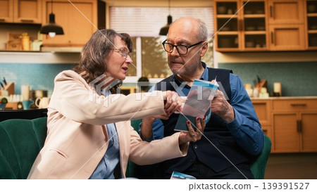 Aged husband and wife reading flyer for medical advice and recommendations, vitamins for wellness and disease prevention. Retired couple focusing on healthcare and daily care routine. Aged husband and wife reading flyer for medical advice and recommendations, vitamins for wellness and disease prevention. Retired couple focusing on healthcare and daily care routine. 139391527