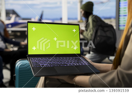 Green screen on laptop in busy airport terminal with passengers ready for departure in international flights, boarding for journey. Waiting area lounge with travelers and luggage, air travel. Green screen on laptop in busy airport terminal with passengers ready for departure in international flights, boarding for journey. Waiting area lounge with travelers and luggage, air travel. 139391539