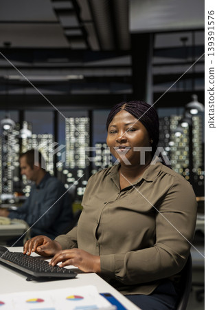 Video creator woman editing a music video on dual monitors in creative office, multitasking between timeline editing and color grading. Professional editor uses tech tools and digital software. 139391576