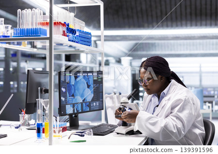 African american chemist analyzing molecular samples in a lab, using professional microscope. Healthcare innovation and biochemistry experiments represent scientific method and discovery. African american chemist analyzing molecular samples in a lab, using professional microscope. Healthcare innovation and biochemistry experiments represent scientific method and discovery. 139391596