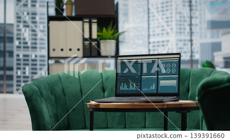 Modern high end empty office space with a laptop running infographics and data reports, professional workspace with screen showcasing the trends for the financial district. Modern high end empty office space with a laptop running infographics and data reports, professional workspace with screen showcasing the trends for the financial district. 139391660