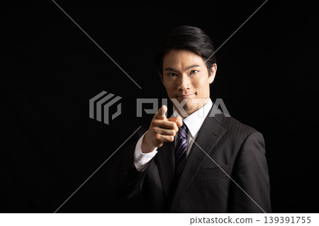 一名男子在黑色背景下指著什麼。 139391755