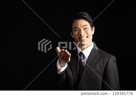 一名男子在黑色背景下指著什麼。 一名男子在黑色背景下指著什麼。 139391778