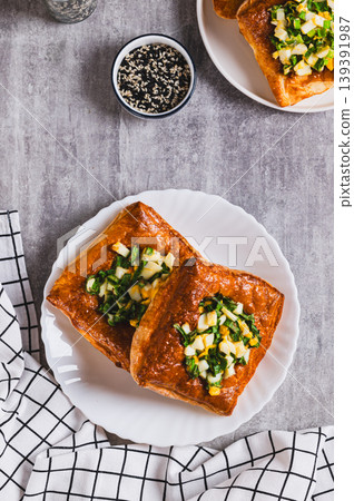 Mini puff pastry tarts with egg and green onions on a plate on the table top and vertical view Mini puff pastry tarts with egg and green onions on a plate on the table top and vertical view 139391987