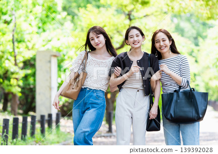 Women walking in a park surrounded by fresh greenery; friends on a girls' trip. 139392028