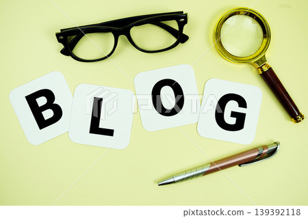BLOG alphabet letters with magnifying glass, eye glasses and pen on yellow background BLOG alphabet letters with magnifying glass, eye glasses and pen on yellow background 139392118