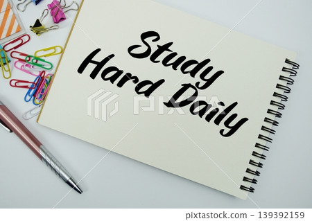 Study Hard Daily text message written on notepad with stationery flat lay on white background Study Hard Daily text message written on notepad with stationery flat lay on white background 139392159