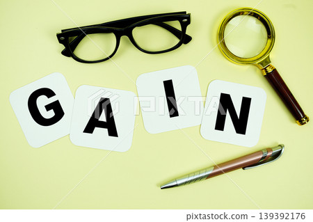 GAIN alphabet letters with magnifying glass, eye glasses and pen on yellow background GAIN alphabet letters with magnifying glass, eye glasses and pen on yellow background 139392176