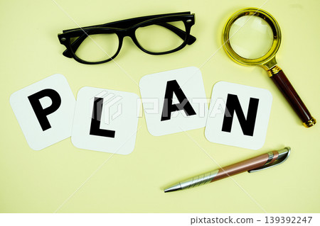 PLAN alphabet letters with magnifying glass, eye glasses and pen on yellow background 139392247