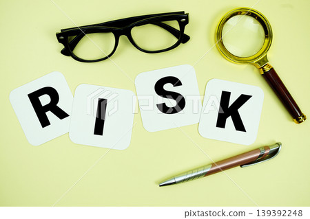 RISK alphabet letters with magnifying glass, eye glasses and pen on yellow background 139392248