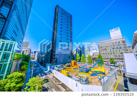 A cityscape of Tokyo, Japan: In front of Shimbashi Station on the Yurikamome Line. Large construction machinery is visible...the Shinkansen bullet train and Toranomon Hills can be seen in the background. A cityscape of Tokyo, Japan: In front of Shimbashi Station on the Yurikamome Line. Large construction machinery is visible...the Shinkansen bullet train and Toranomon Hills can be seen in the background. 139393520