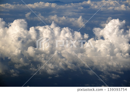 Aerial view from above at high altitude of dense puffy cumulus clouds flying. Amazing from airplane window point of view 139393754