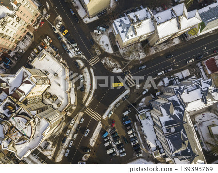 Aerial black and white winter top view of modern city with tall buildings, parked and moving cars along streets with road marking. Urban cityscape, view from above. 139393769