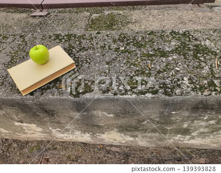 Green Apple on a Closed Book on Mossy Concrete Green Apple on a Closed Book on Mossy Concrete 139393828