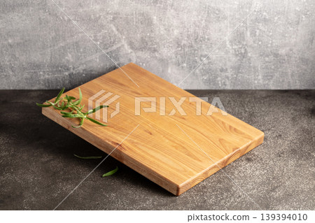 Empty cutting board with rosemary on a grey stone background. 139394010