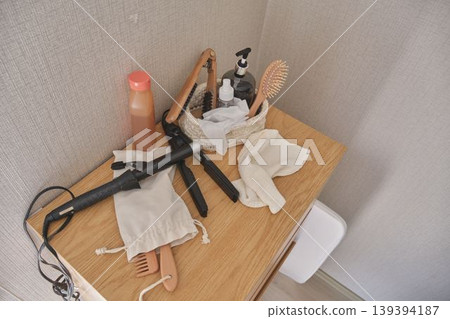 Hair styling tools and beauty products on wooden dresser 139394187