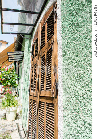 A building with pastel-colored walls and flowers in potted plants under bright sunlight on the French island of Corsica in the Mediterranean Sea. A building with pastel-colored walls and flowers in potted plants under bright sunlight on the French island of Corsica in the Mediterranean Sea. 139394285