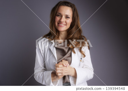 Friendly Female Physician Standing with Clasped Hands Friendly Female Physician Standing with Clasped Hands 139394548