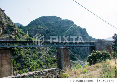 A river flowing through the mountains and a large, historic stone bridge on the French island of Corsica in the Mediterranean Sea. A river flowing through the mountains and a large, historic stone bridge on the French island of Corsica in the Mediterranean Sea. 139394578