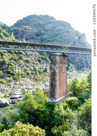 A river flowing through the mountains and a large, historic stone bridge on the French island of Corsica in the Mediterranean Sea. 139394579