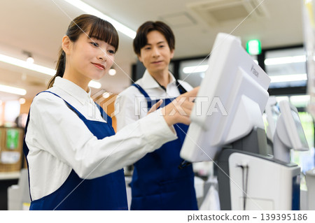 一男一女正在商店操作收銀機。 139395186