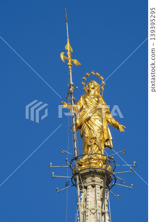 Madonnina golden statue of Virgin Mary on top of Milan Gothic Church sunny day 139395295