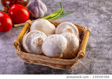 Fresh champignon mushrooms in a wicker basket with tomatoes and garlic on a gray table 139395369