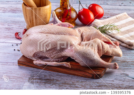 Whole raw duck prepared for roasting with tomatoes, garlic, rosemary, and spices on a rustic table Whole raw duck prepared for roasting with tomatoes, garlic, rosemary, and spices on a rustic table 139395376