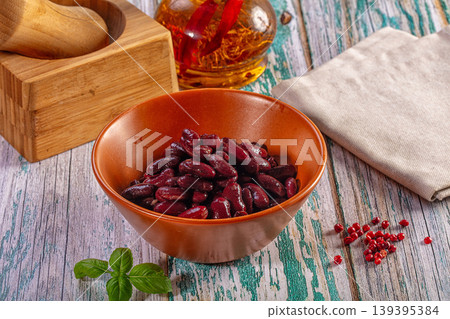 Cooked red kidney beans in a brown bowl with spices and herbs on a rustic wooden surface Cooked red kidney beans in a brown bowl with spices and herbs on a rustic wooden surface 139395384