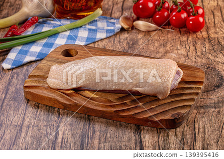 Raw duck breast fillet on wooden board with fresh vegetables and olive oil Raw duck breast fillet on wooden board with fresh vegetables and olive oil 139395416