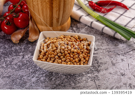 Soybeans in white bowl with fresh cherry tomatoes, garlic, chili peppers, green onions on textured surface Soybeans in white bowl with fresh cherry tomatoes, garlic, chili peppers, green onions on textured surface 139395419