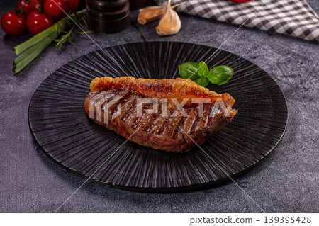 Juicy Grilled Steak with Golden Fat Cap, Fresh Basil, and Cherry Tomatoes on Dark Plate Juicy Grilled Steak with Golden Fat Cap, Fresh Basil, and Cherry Tomatoes on Dark Plate 139395428