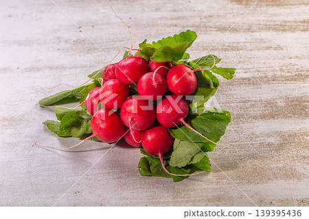Fresh red radishes bunch, vibrant green leaves, rustic wooden background Fresh red radishes bunch, vibrant green leaves, rustic wooden background 139395436