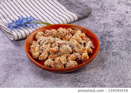 Sesame coated peanuts in wooden bowl with striped napkin and blue flowers Sesame coated peanuts in wooden bowl with striped napkin and blue flowers 139395438
