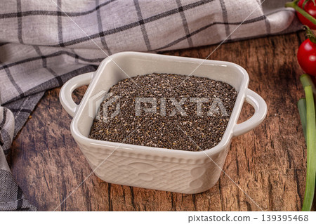 Chia seeds in white bowl on rustic wooden table, fresh vegetables surrounding, healthy superfood Chia seeds in white bowl on rustic wooden table, fresh vegetables surrounding, healthy superfood 139395468