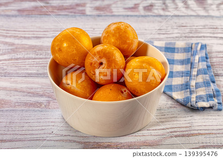 Bowl of fresh yellow plums on distressed wood background with napkin 139395476