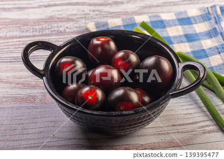Ripe black cherry tomatoes in dark bowl with scallions on rustic wood background Ripe black cherry tomatoes in dark bowl with scallions on rustic wood background 139395477