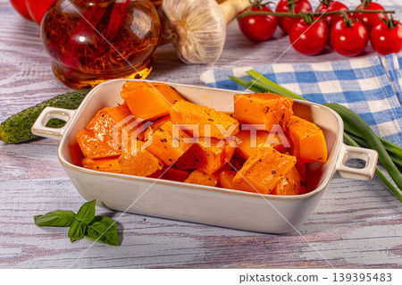 Roasted butternut squash with herbs in ceramic dish surrounded by fresh vegetables Roasted butternut squash with herbs in ceramic dish surrounded by fresh vegetables 139395483