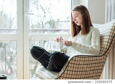 Woman knitting new sweater with gray yarn at home Woman knitting new sweater with gray yarn at home 139395575