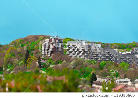 Modern apartment buildings nestled in a lush green hillside landscape Modern apartment buildings nestled in a lush green hillside landscape 139396660