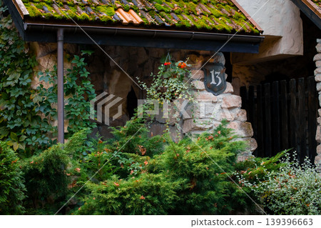 manor charming stone house with a mossy roof and lush greenery medieval aesthetic architecture featuring a house number 13 on the wall 139396663