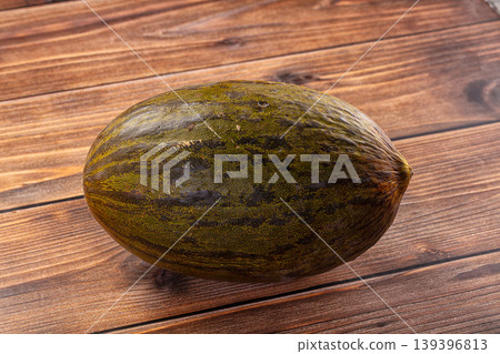 Whole Piel de Sapo melon, also known as Santa Claus melon, on a rustic wooden table background. Whole Piel de Sapo melon, also known as Santa Claus melon, on a rustic wooden table background. 139396813