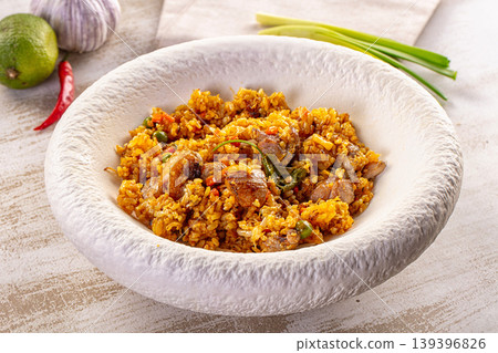 Flavorful rice dish with meat and peas, resembling paella, in a textured white bowl Flavorful rice dish with meat and peas, resembling paella, in a textured white bowl 139396826