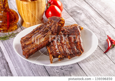 Roasted pork ribs with spices, tomatoes, and garlic on a rustic wooden table Roasted pork ribs with spices, tomatoes, and garlic on a rustic wooden table 139396850