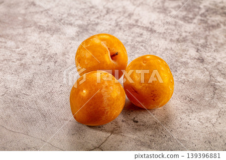 Three fresh yellow plums on gray textured background. Ripe organic stone fruit still life Three fresh yellow plums on gray textured background. Ripe organic stone fruit still life 139396881