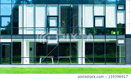 Modern glass facade building with green lawn in front on a sunny day Modern glass facade building with green lawn in front on a sunny day 139396917