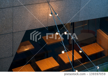 Garland string light hanging above table in a modern outdoor seating area at night Garland string light hanging above table in a modern outdoor seating area at night 139397059