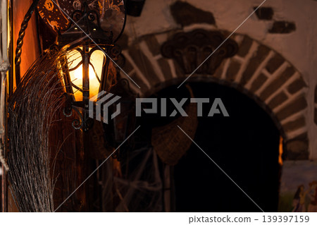 Spooky Halloween lantern and broomstick decoration casting warm light at dusk 139397159